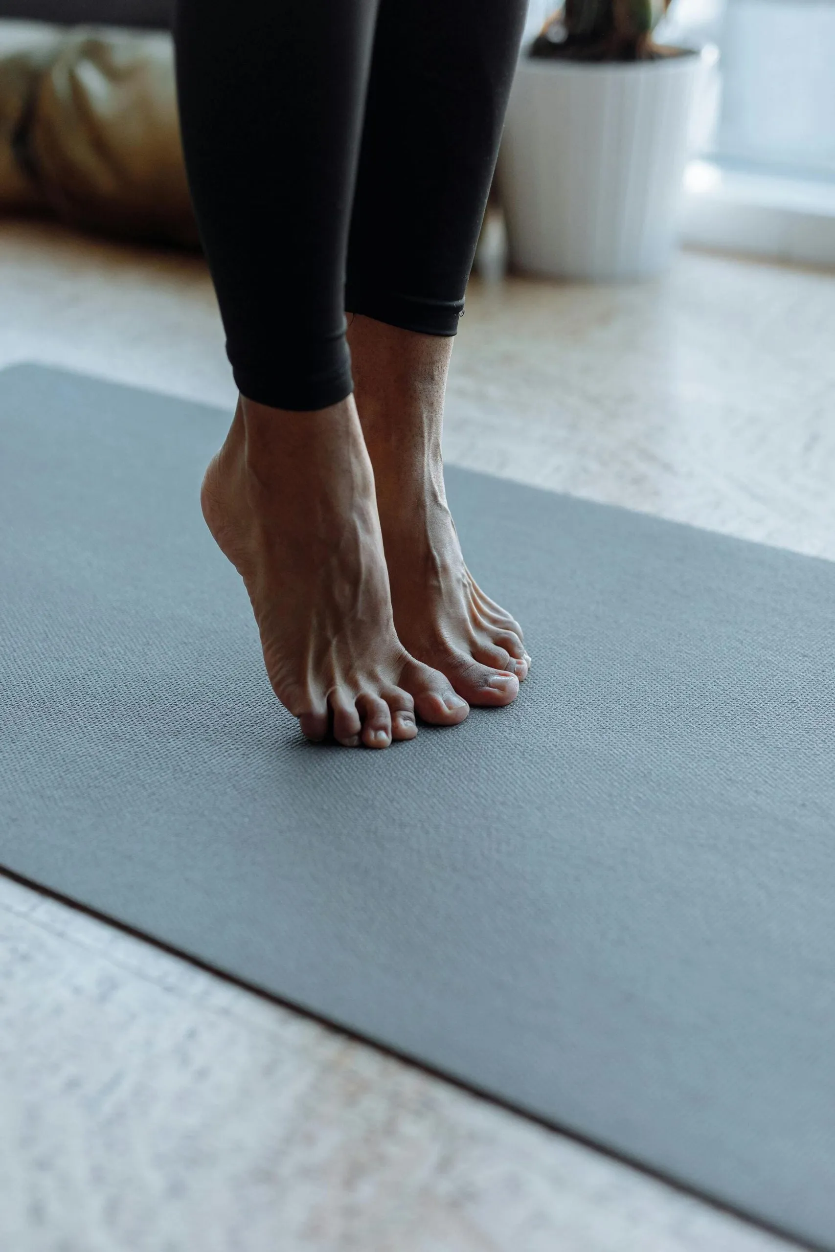 Un tapis de yoga gris et deux pieds joints en appui sur la pointe