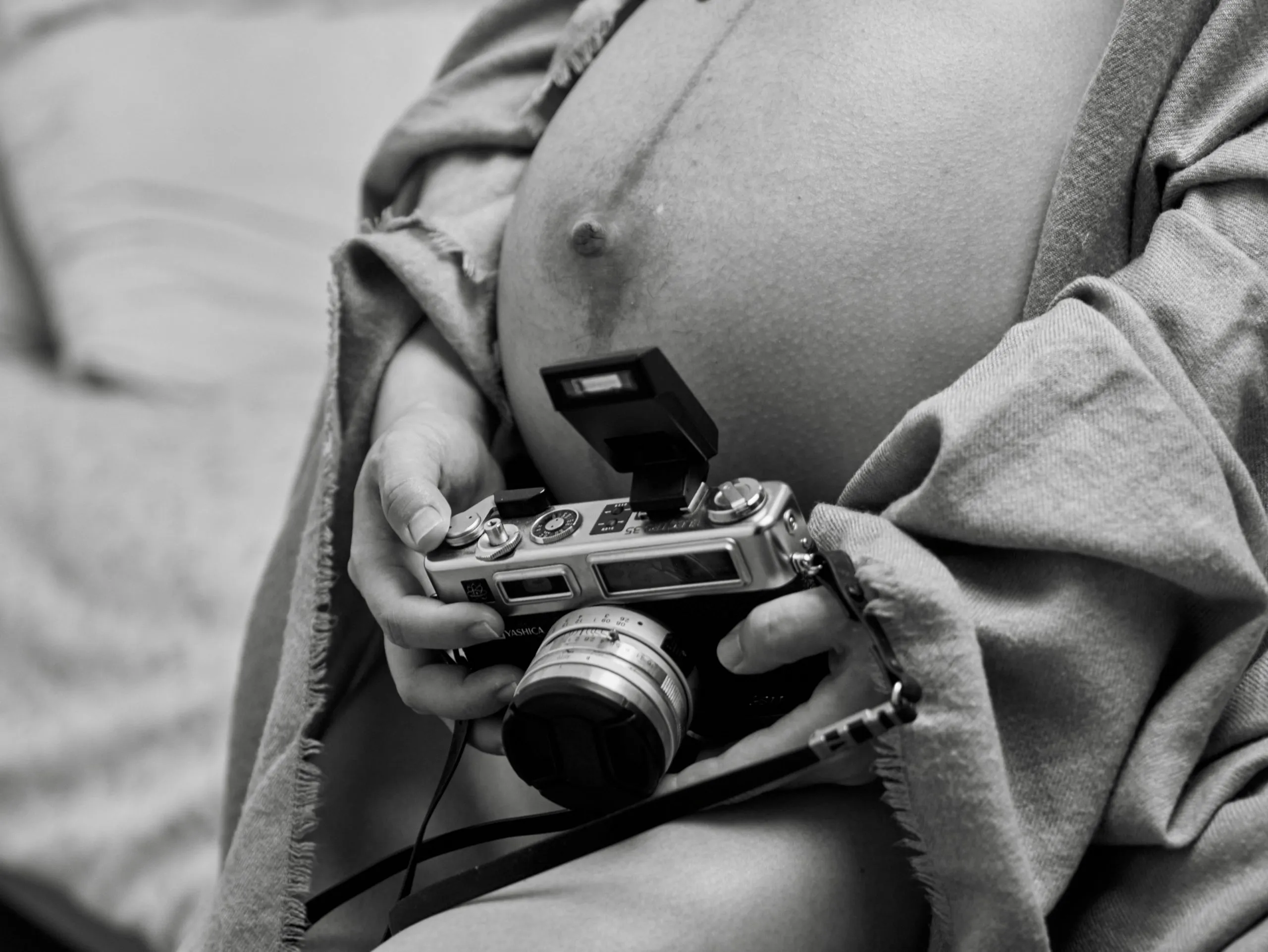 Une femme enceinte tenant un appareil photo argentique, en noir et blanc