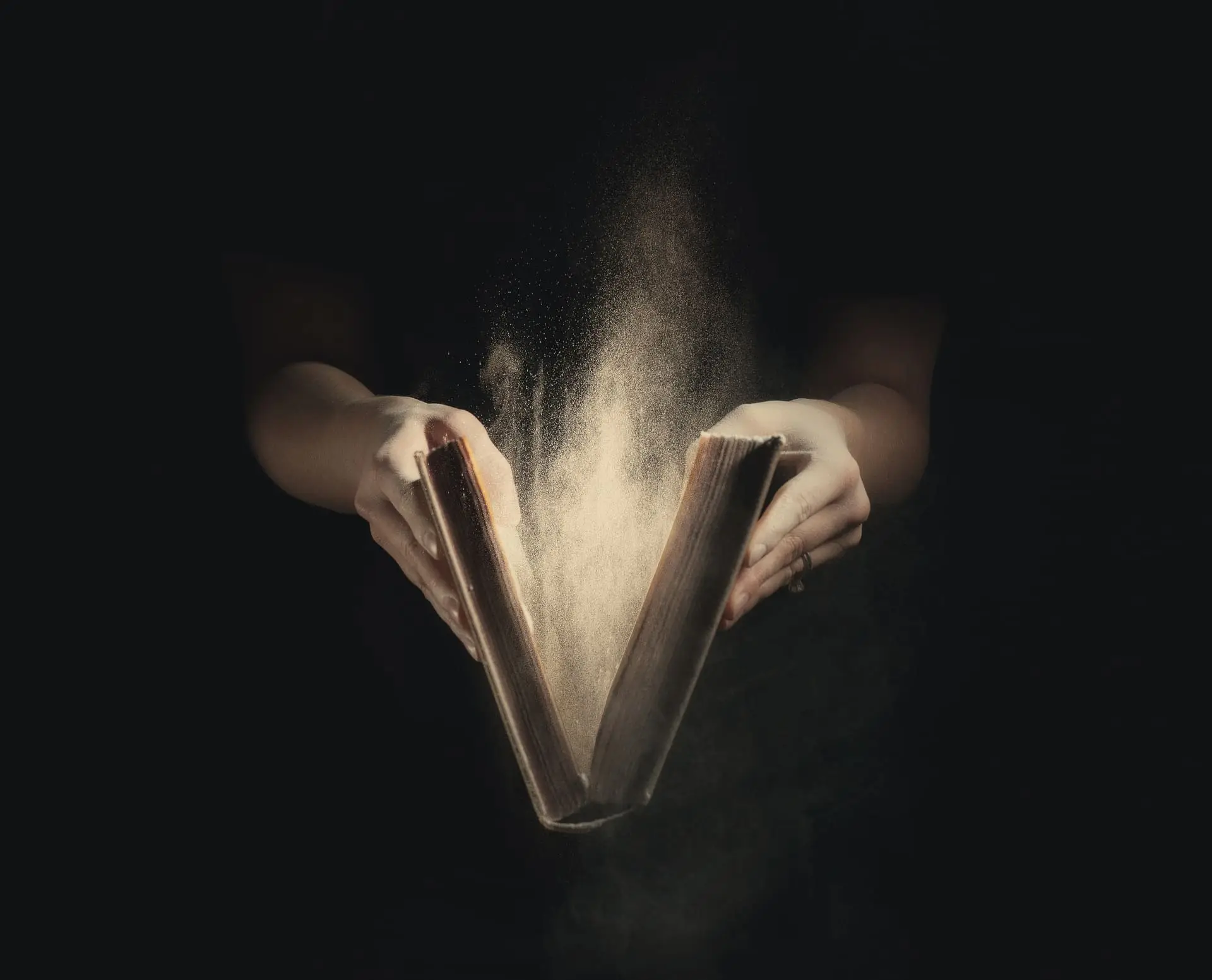 Livre ancien ouvert avec de la poussière éclairé dans le noir